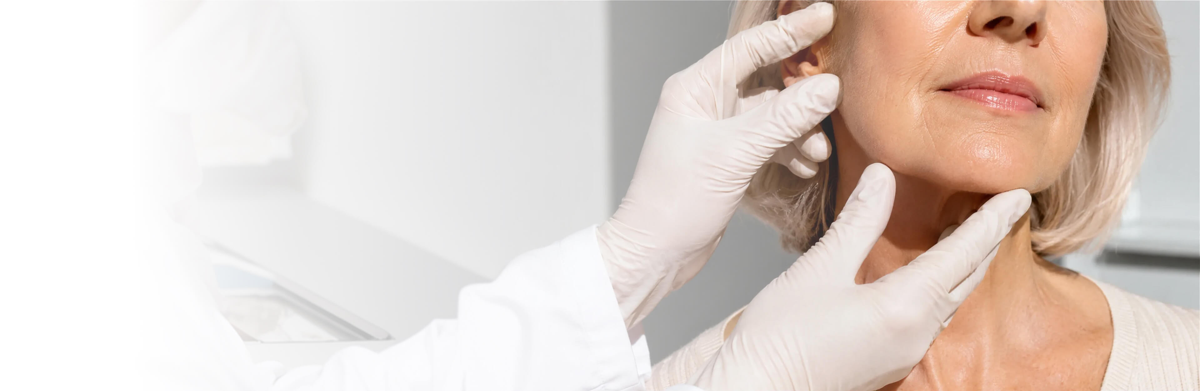 Dermatologist examining a patient's face and neck at Coral Dermatology